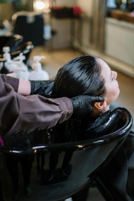 A professional hairstylist washing a woman's hair in a modern salon setting, ensuring quality haircare.