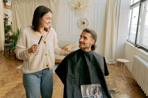 A woman hairdresser styling a man's hair in a luxurious salon, creating a warm, relaxed atmosphere.